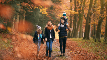 Familie geht in den Herbstferien durch den Wald spazieren, Ferienabenteuer 2024